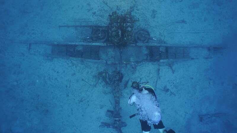 diver underwater looking down at plane reckage